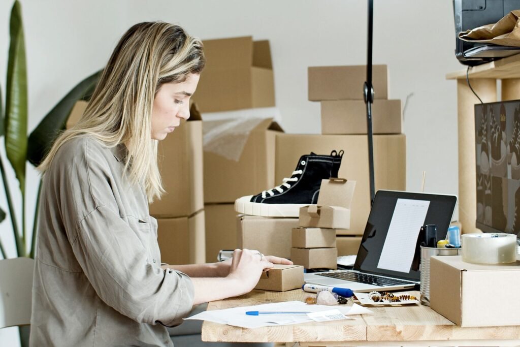 Small business owner packing online store orders at a desk with a laptop